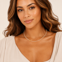 Model wearing pearl necklace with gold cross